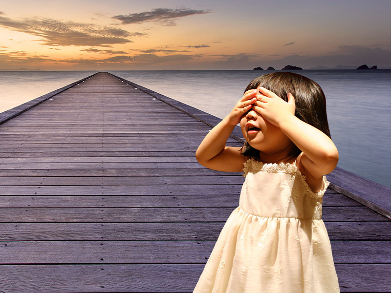 Une petite fille se cache les yeux sur un quai