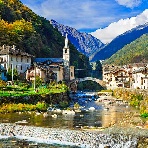Panorama époustouflant d'un rivière   avec son pont de briques, d'une église le tout au centre de majestueuses montagnes